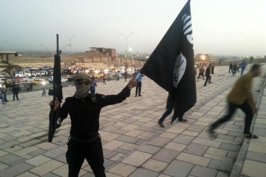 File image of an Islamic State of Iraq and the Levant (ISIL) militant holding an ISIL flag and a weapon on a street in the city of Mosul (Reuters)